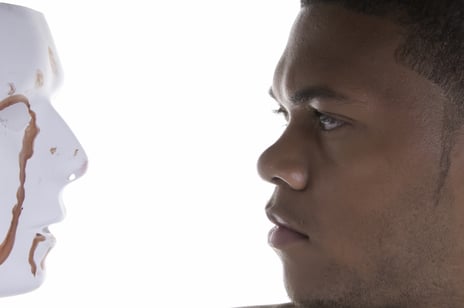 Young black man contemplates blood-stained mask