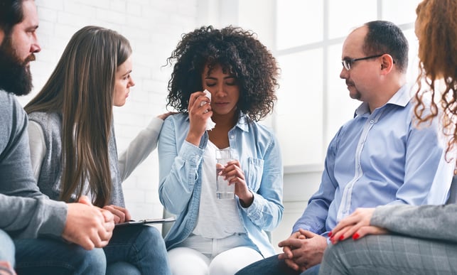 black woman crying in couples workshop while white people comfort her